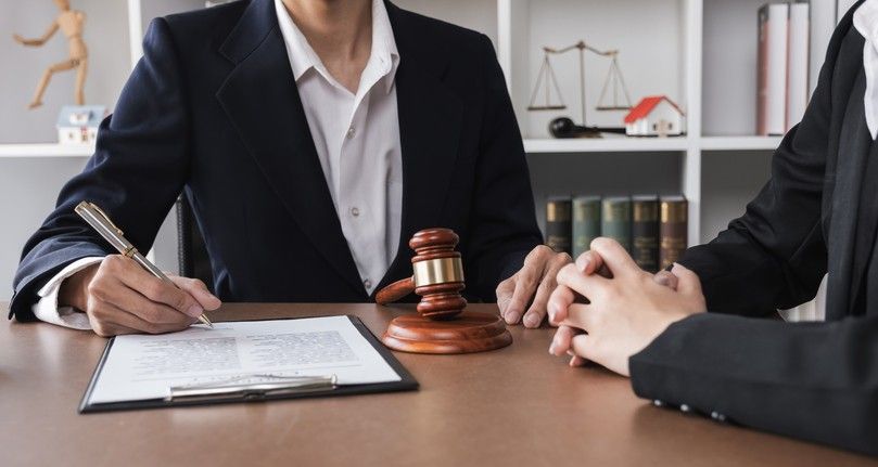 Attorney consulting with a client across a desk with a judge’s gavel and legal documents, representing legal defense for Michigan police officers during internal investigations