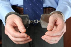 Man in a business suit wearing handcuffs representing theft or fraud charges in Michigan