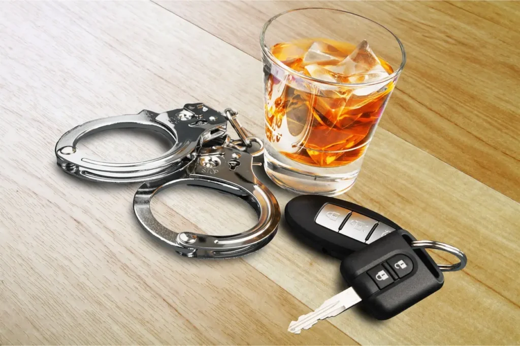 Handcuffs, alcohol, and car keys representing DUI, MIP, or assault charges for Michigan college students.